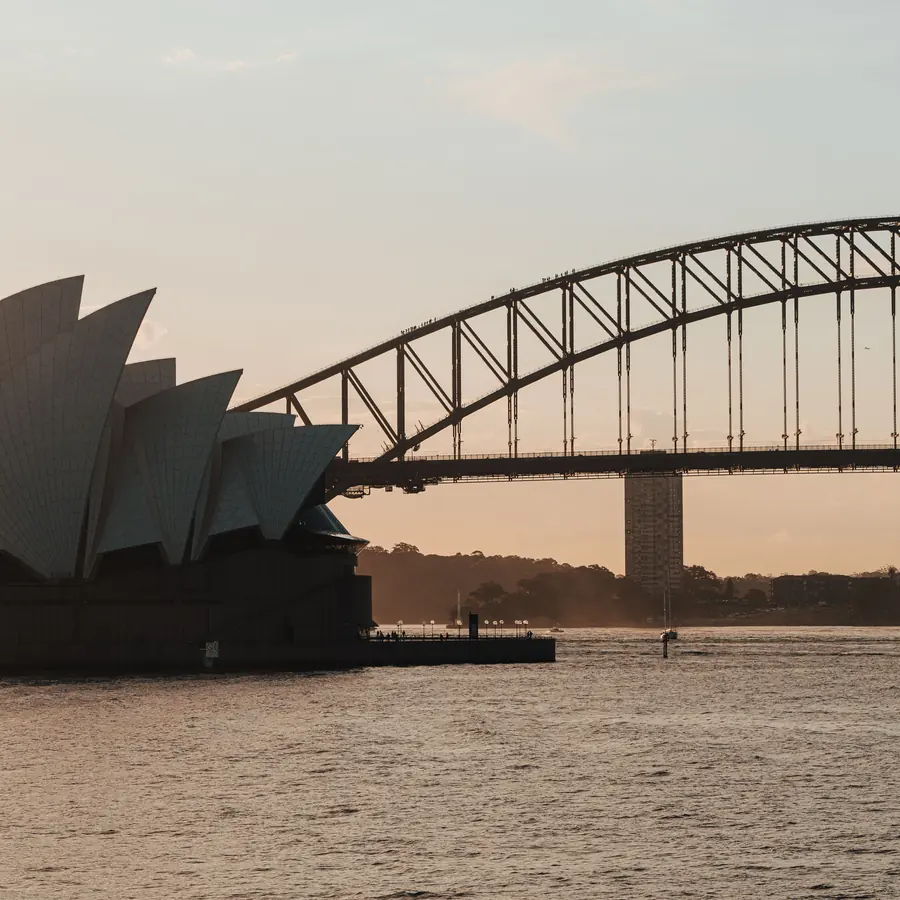 A scenic view of Sydney Opera House and Harbour Bridge at dusk, captured on a tranquil evening