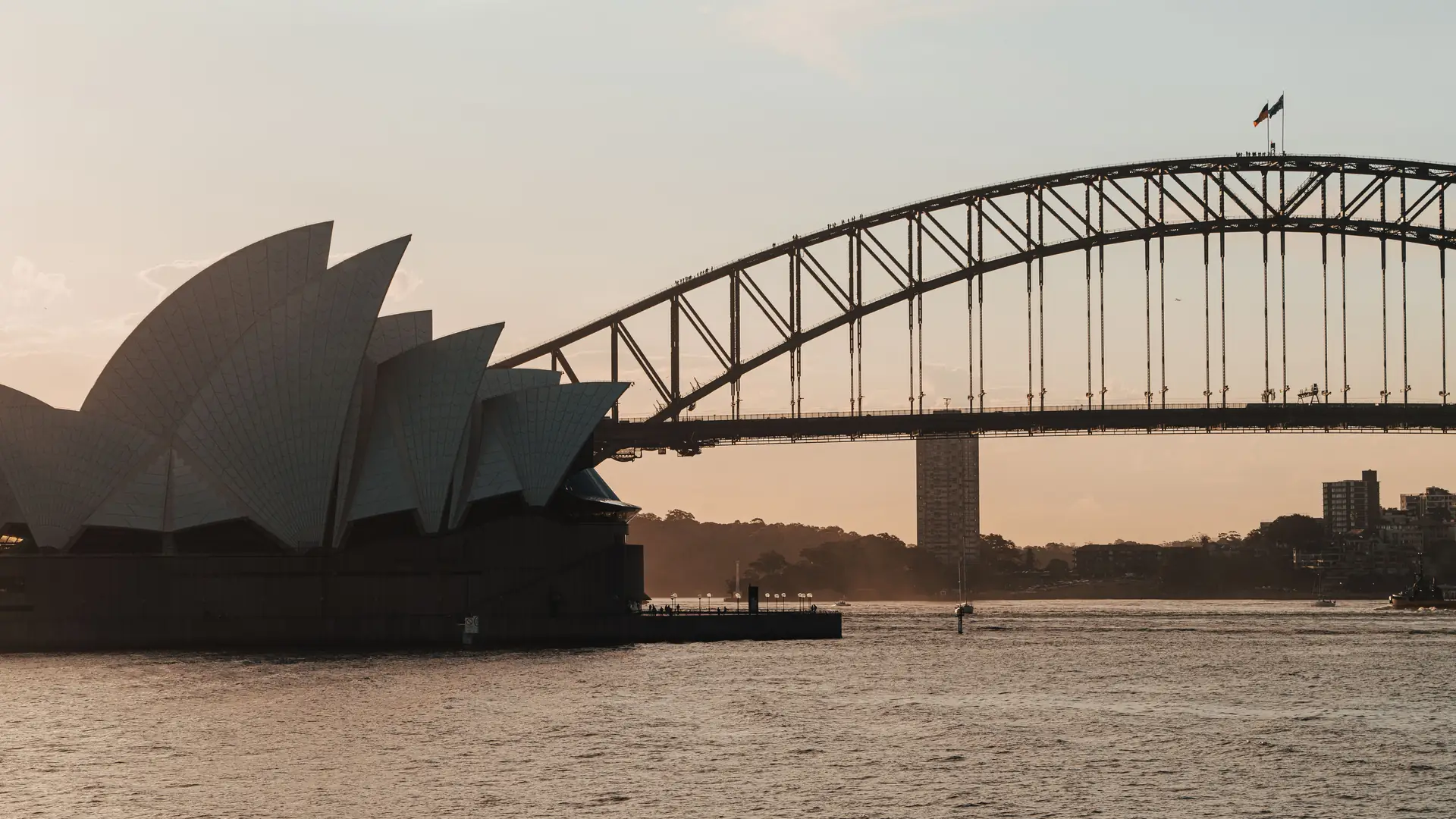 A scenic view of Sydney Opera House and Harbour Bridge at dusk, captured on a tranquil evening