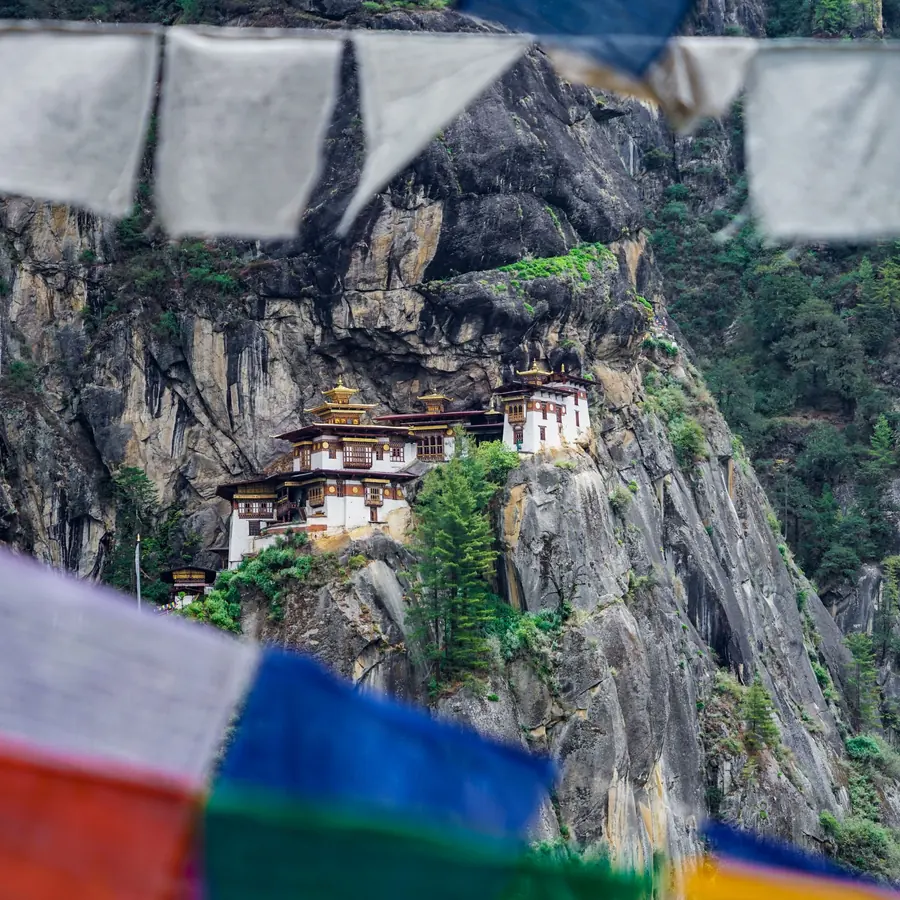 A stunning view of Paro Taktsang Monastery nestled in the cliffs of Bhutan with vibrant prayer flags