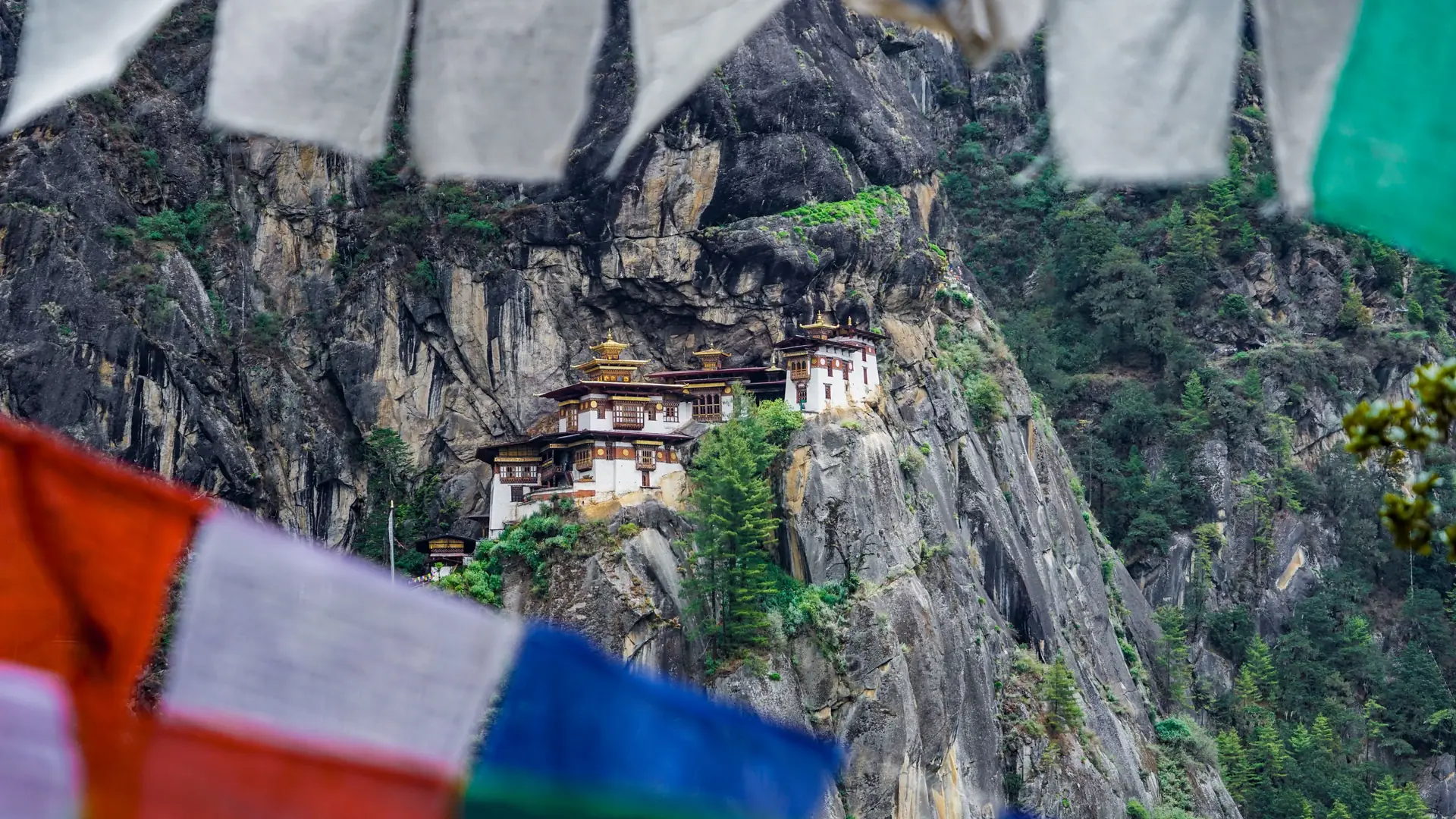 A stunning view of Paro Taktsang Monastery nestled in the cliffs of Bhutan with vibrant prayer flags
