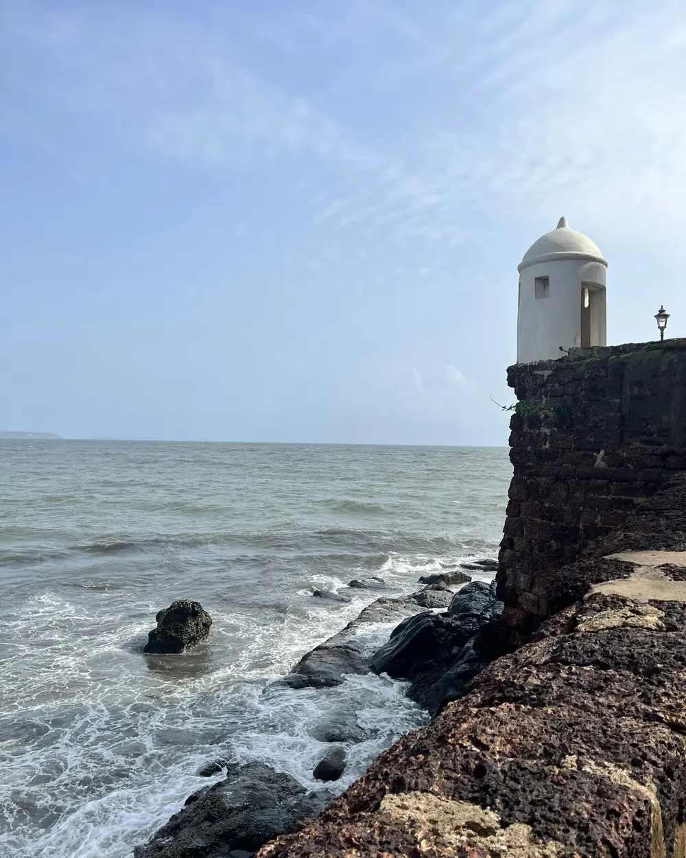 a lighthouse on the edge of a cliff near the ocean