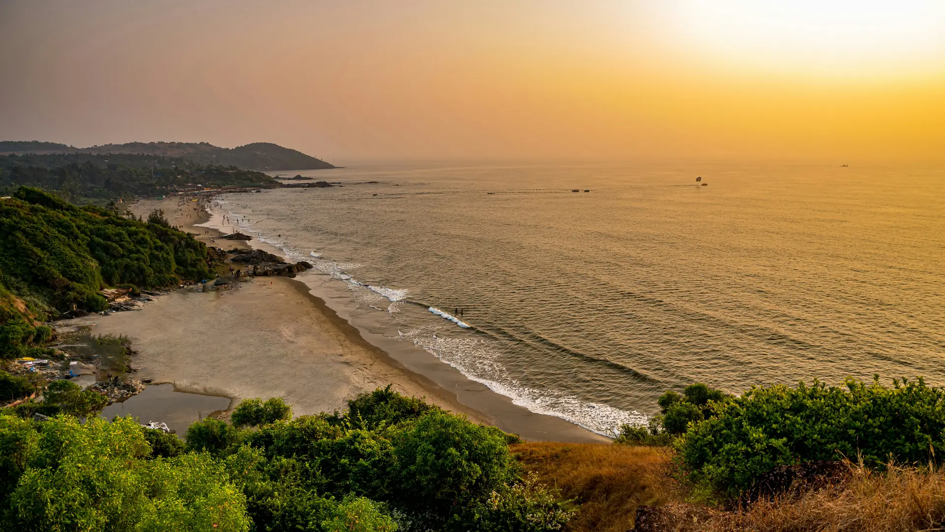 the sun is setting over the ocean and a beach