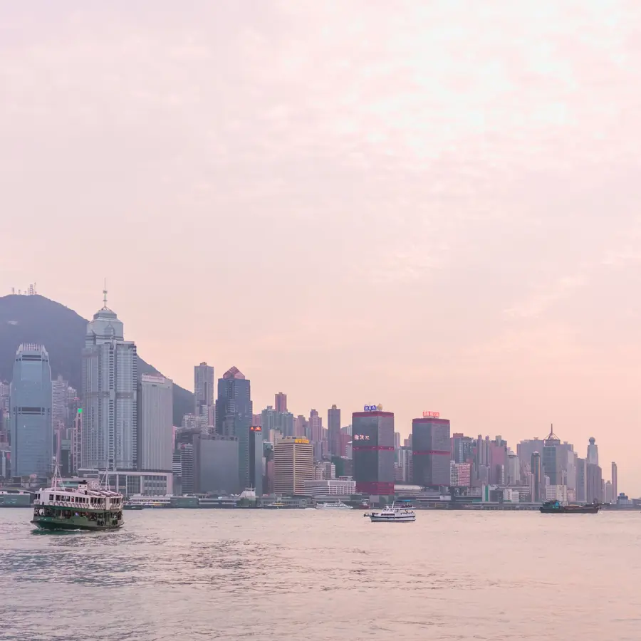 Serene view of the Hong Kong skyline at sunset with boats on Victoria Harbour