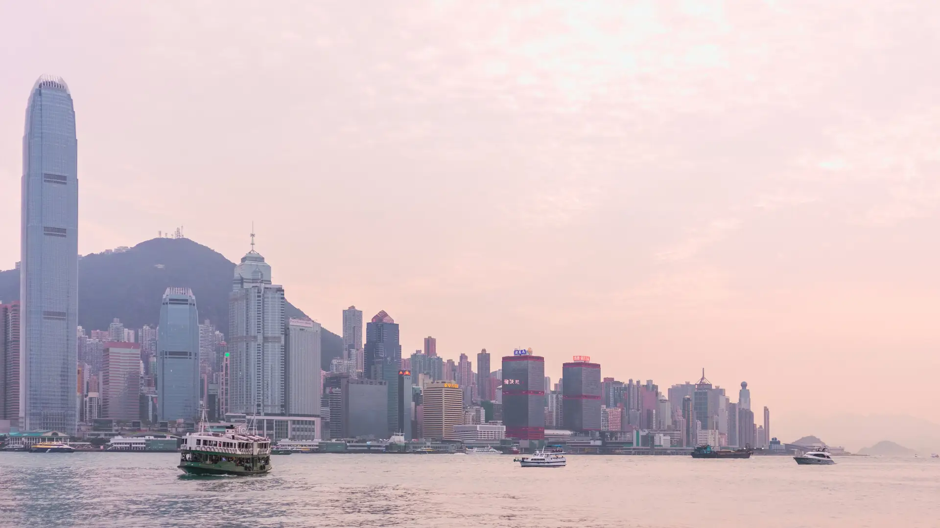Serene view of the Hong Kong skyline at sunset with boats on Victoria Harbour