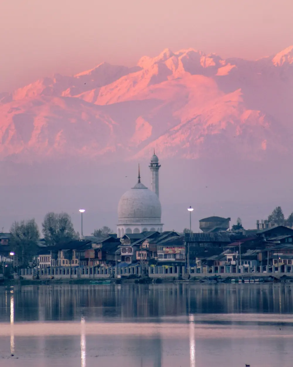 A breathtaking view of Hazratbal Shrine with snowcapped mountains at sunset in Srinagar, India