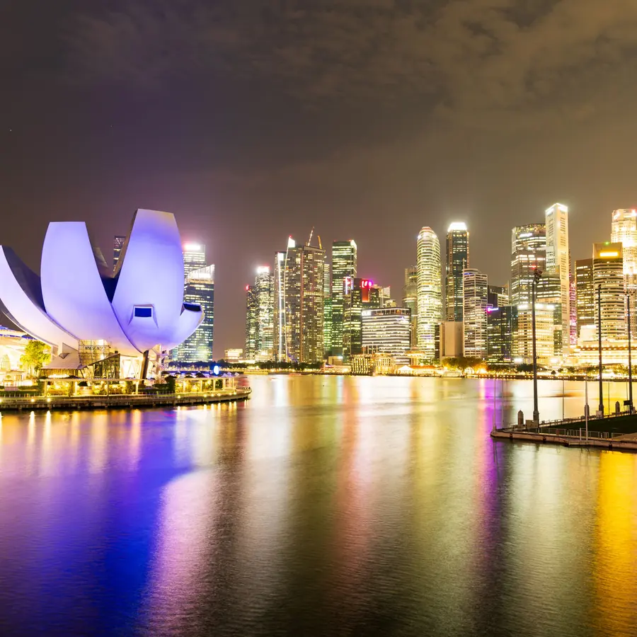 Night view of Singapore's illuminated skyline and Marina Bay Sands, reflecting vibrant city lights