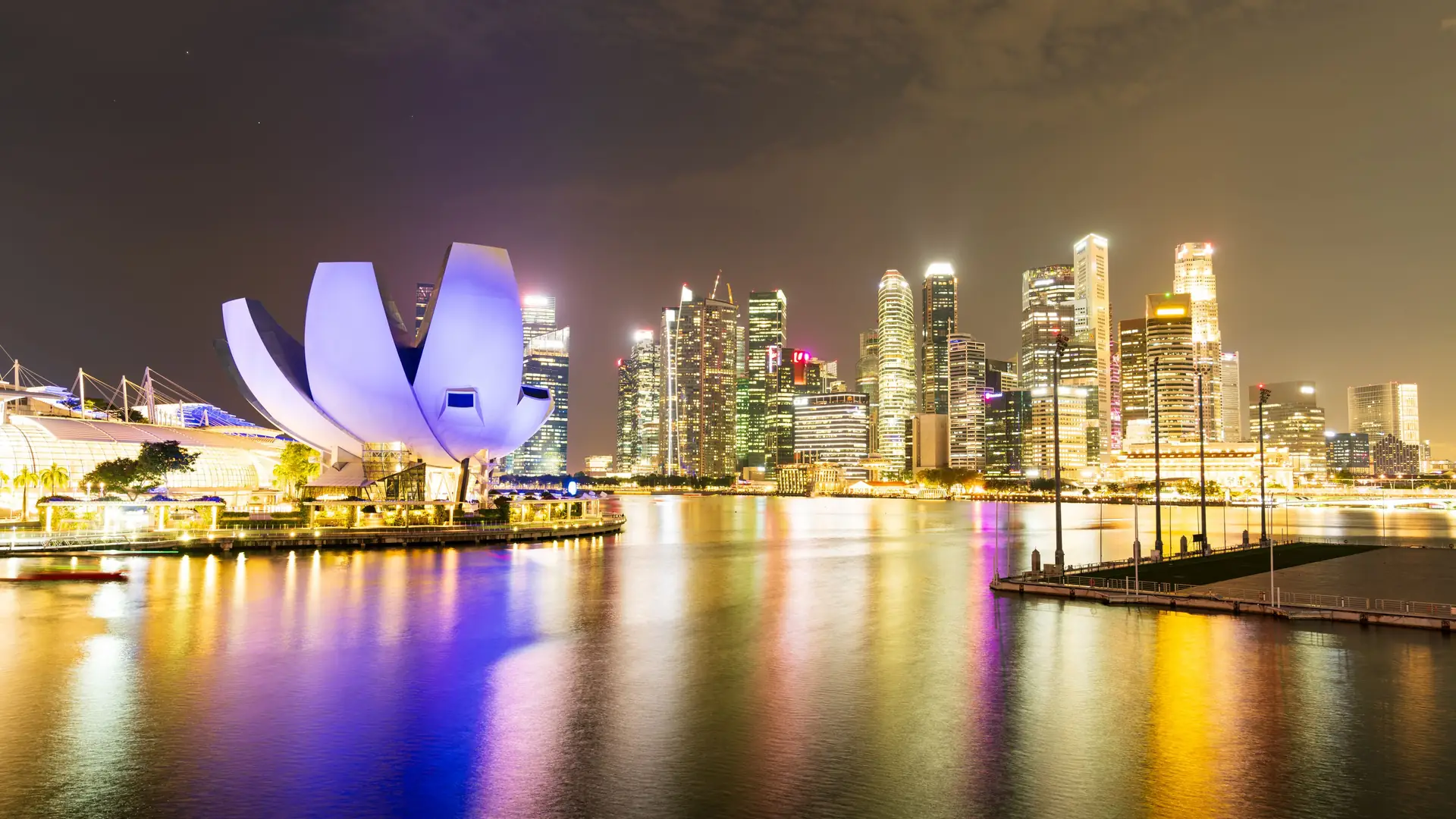 Night view of Singapore's illuminated skyline and Marina Bay Sands, reflecting vibrant city lights