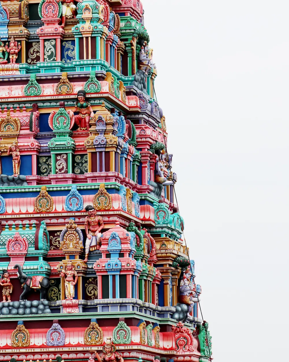 Vibrant facade of Meenakshi Temple's gopura in Madurai, India, showcasing intricate Hindu art